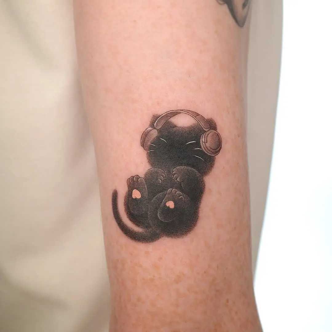 Adorable black cat tattoo wearing headphones