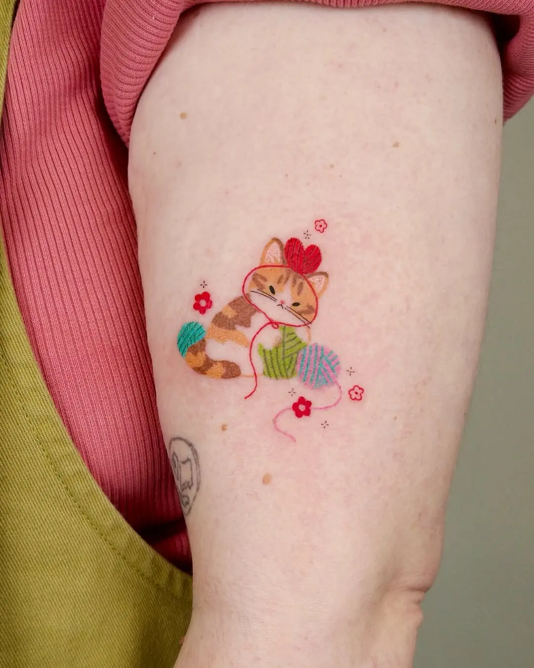 Playful cat tattoo with yarn and flowers