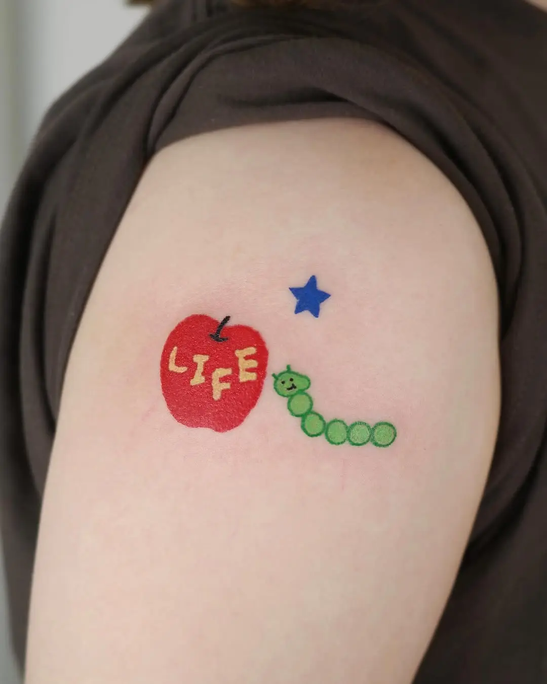 Playful apple and worm tattoo design