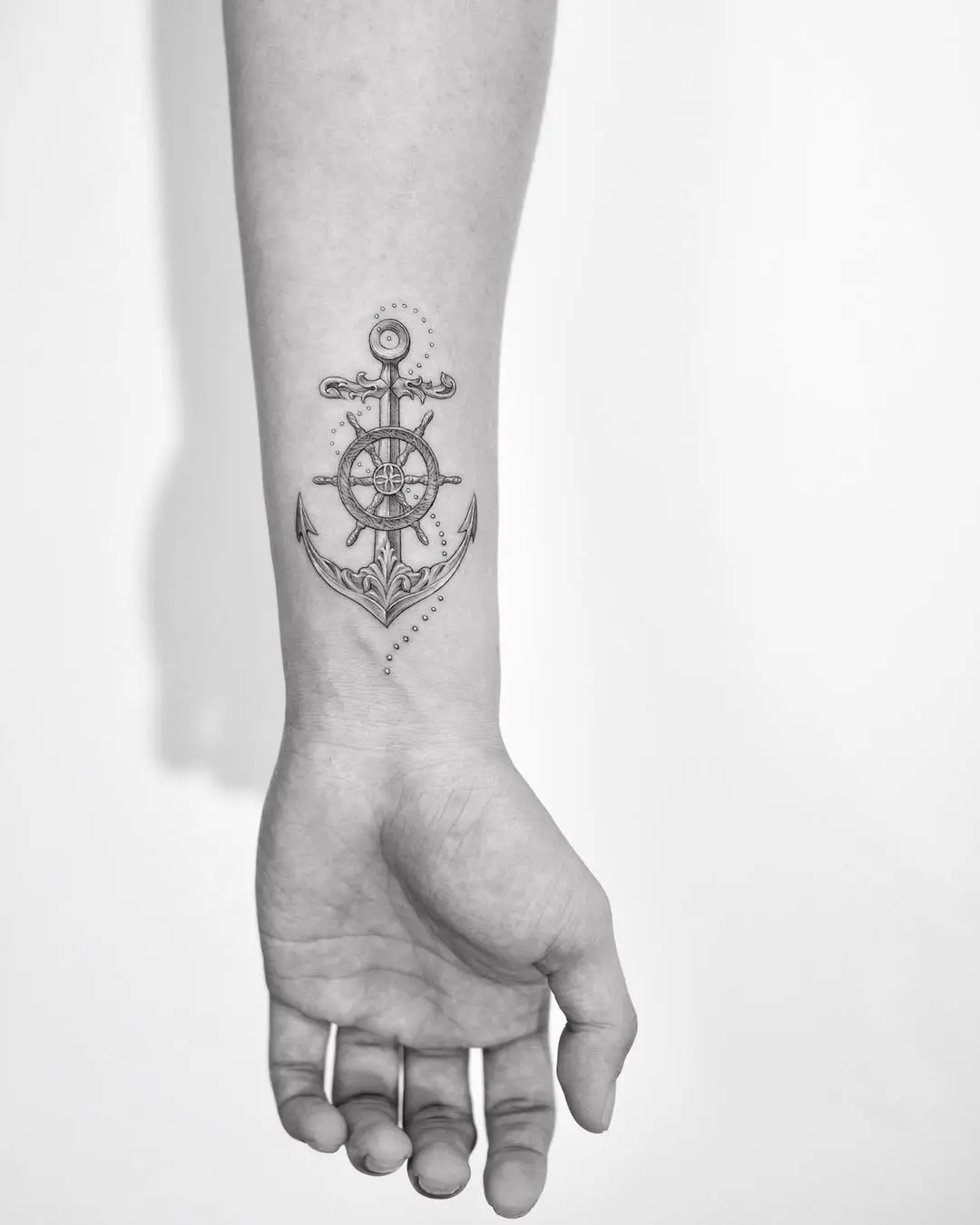 Stylish anchor and wheel tattoo on forearm