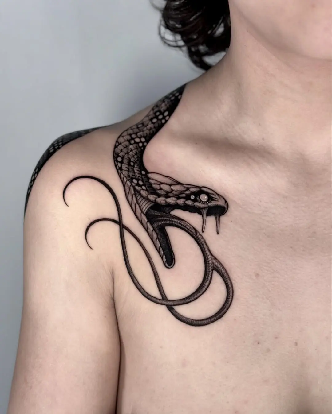 Intricate black snake tattoo on shoulder area