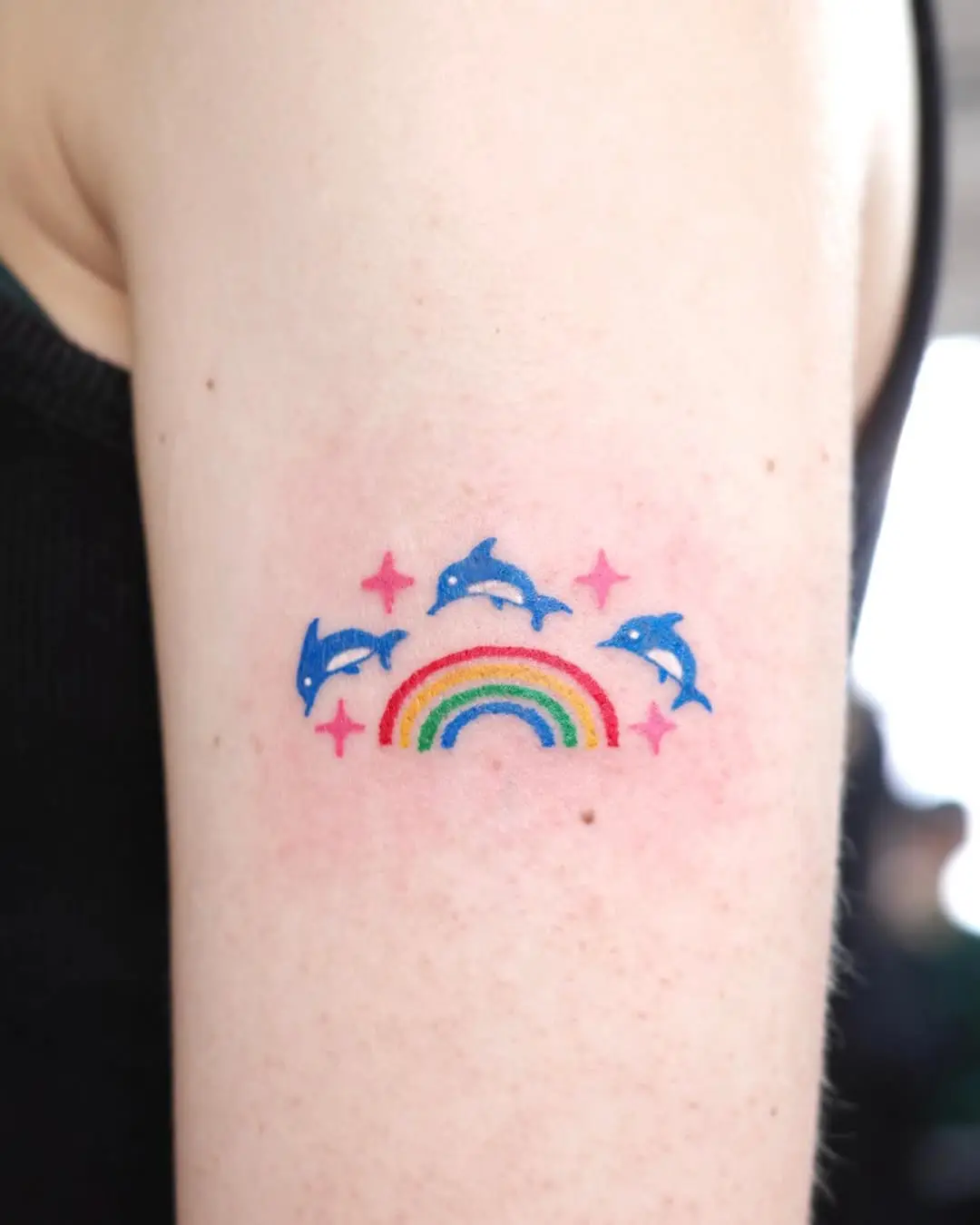Playful dolphin tattoo with rainbow and stars