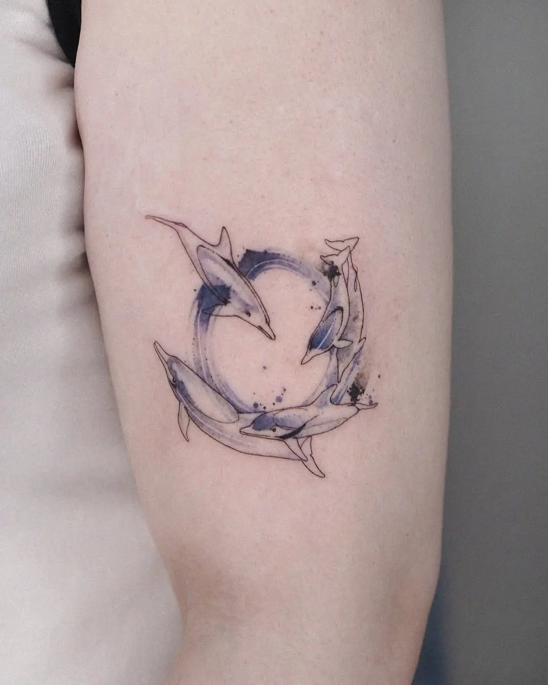 Whimsical dolphin tattoo in circular watercolor design