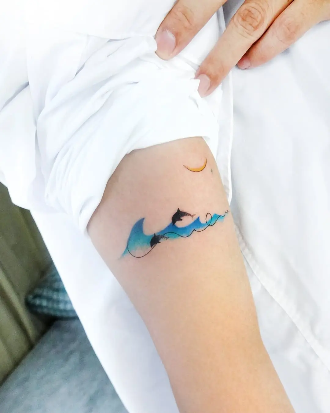 Whimsical dolphin tattoo with ocean waves