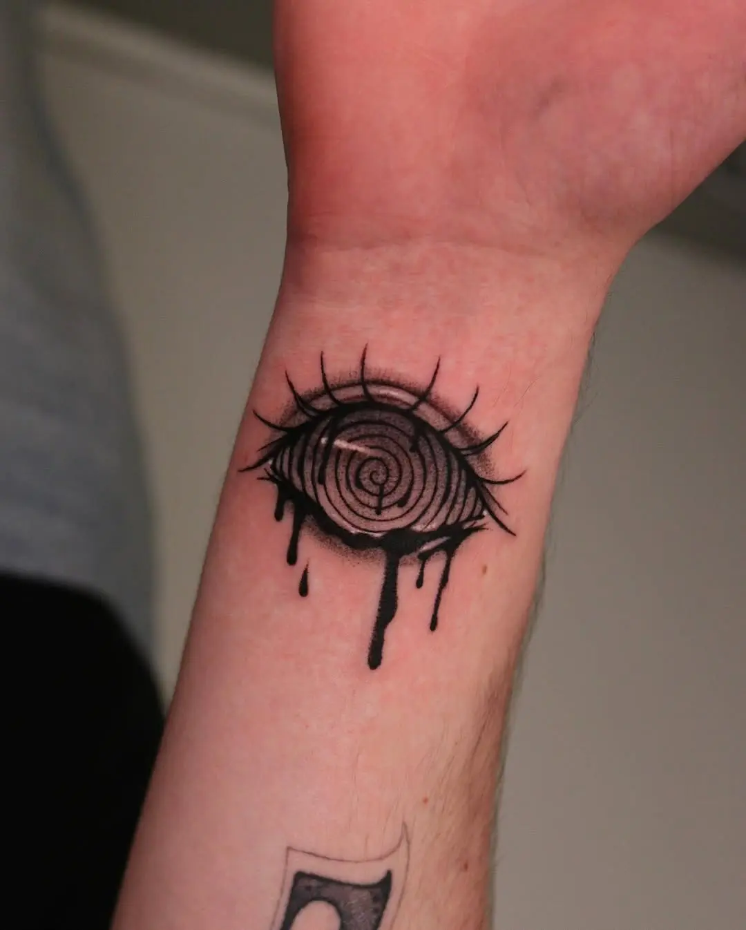 Striking spiral eye tattoo with dripping detail