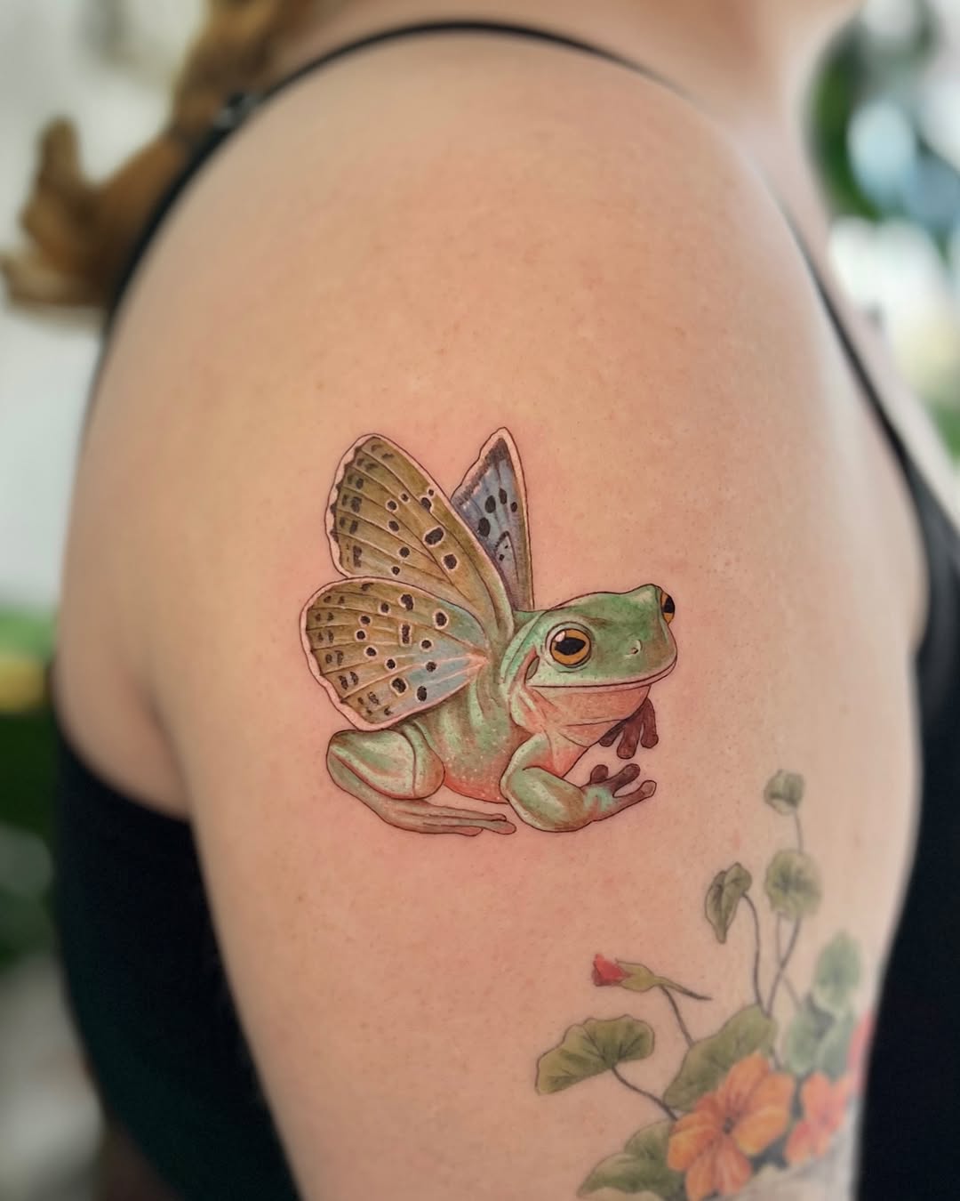 Whimsical frog tattoo with colorful wings
