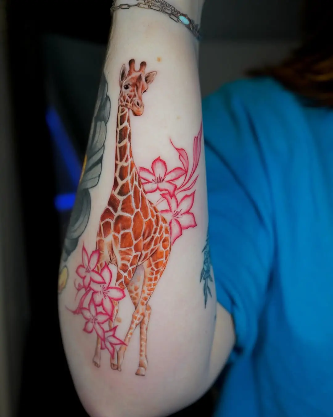 Vibrant giraffe surrounded by floral elements tattoo