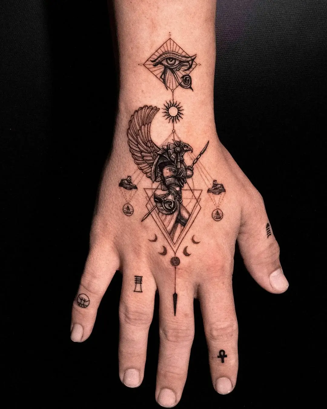 Intricate Egyptian symbols grace this hand tattoo