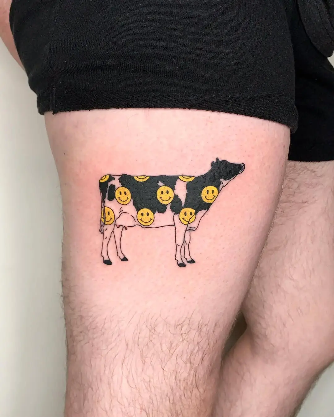 Whimsical cow tattoo with cheerful smilies