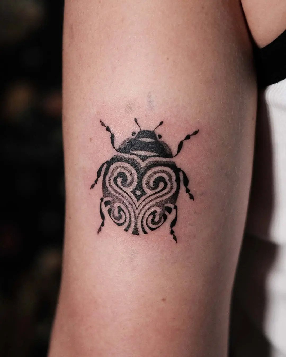 Elegant tribal ladybug tattoo in black ink