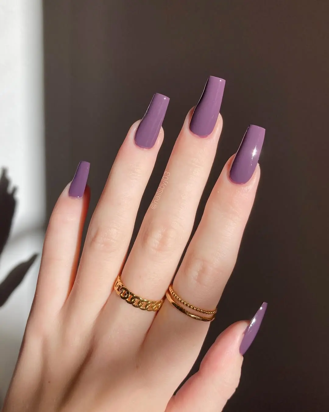 Elegant mauve nails adorned with gold rings