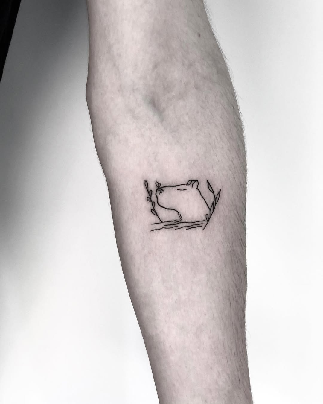 Elegant line art capybara tattoo surrounded by foliage