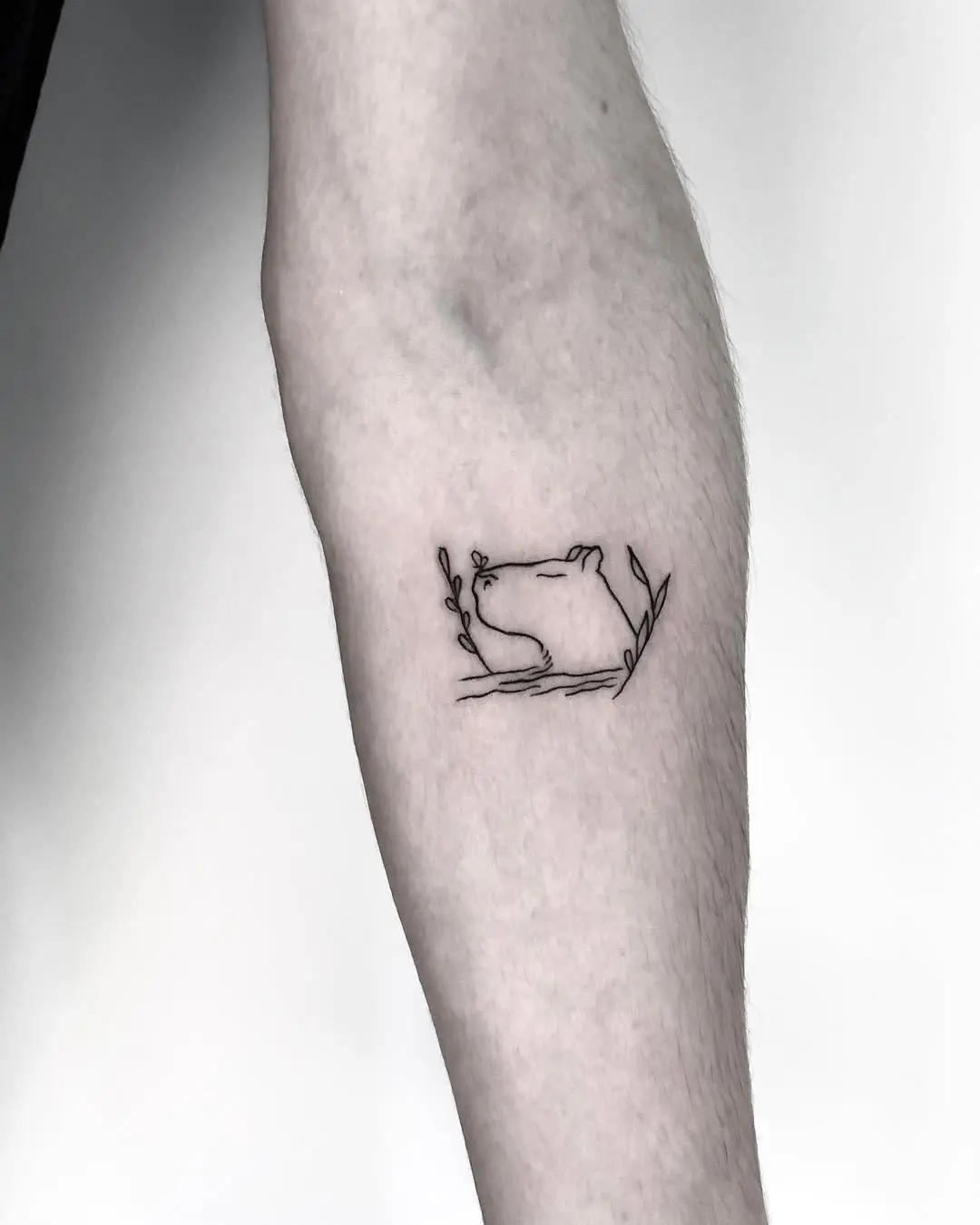 Elegant line art capybara tattoo surrounded by foliage