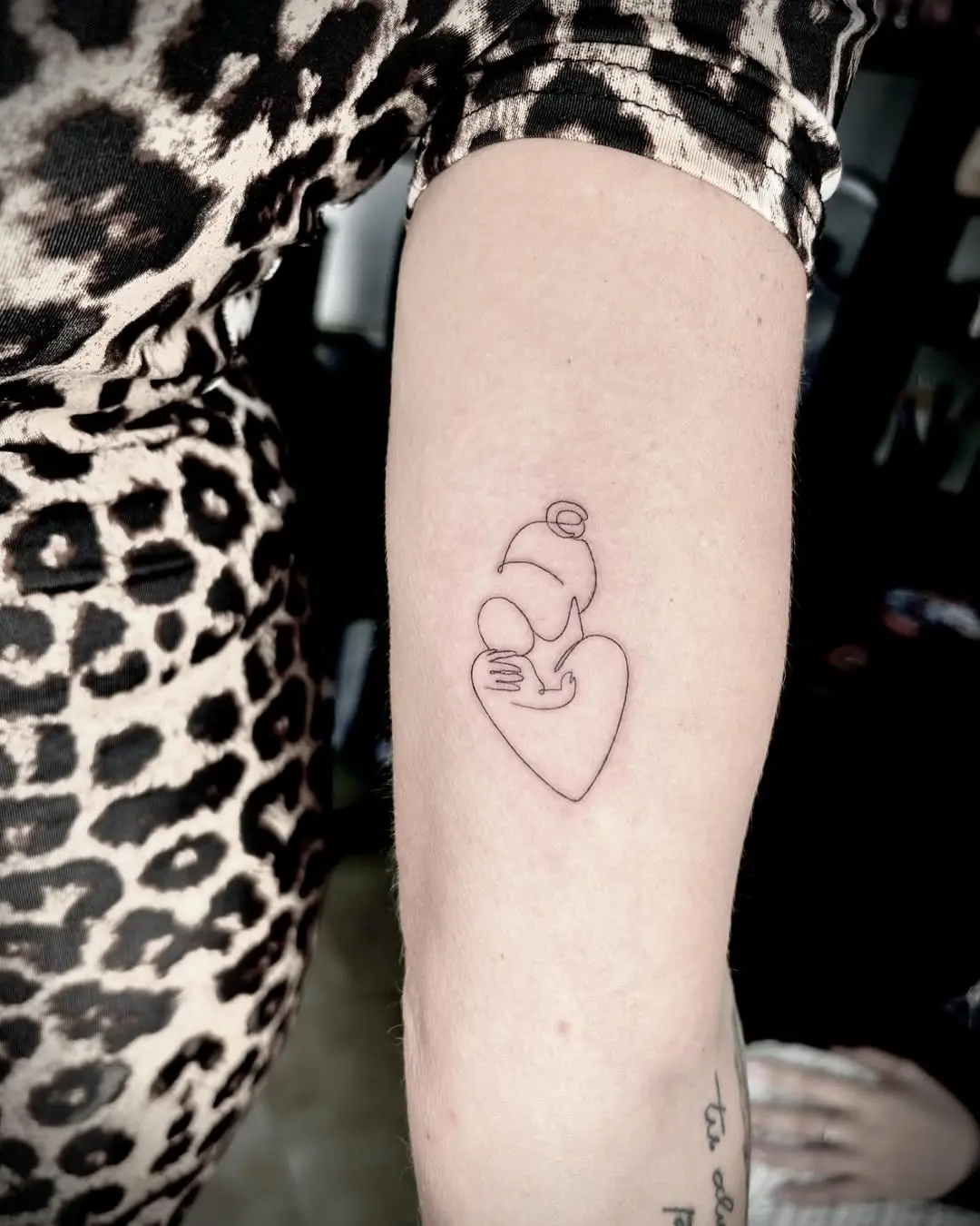 Delicate mother-and-child line art tattoo