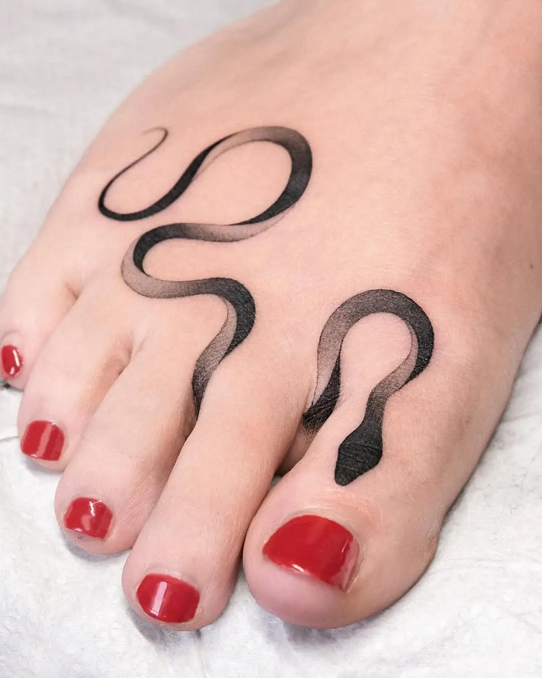 Elegant snake tattoo wrapping around the foot