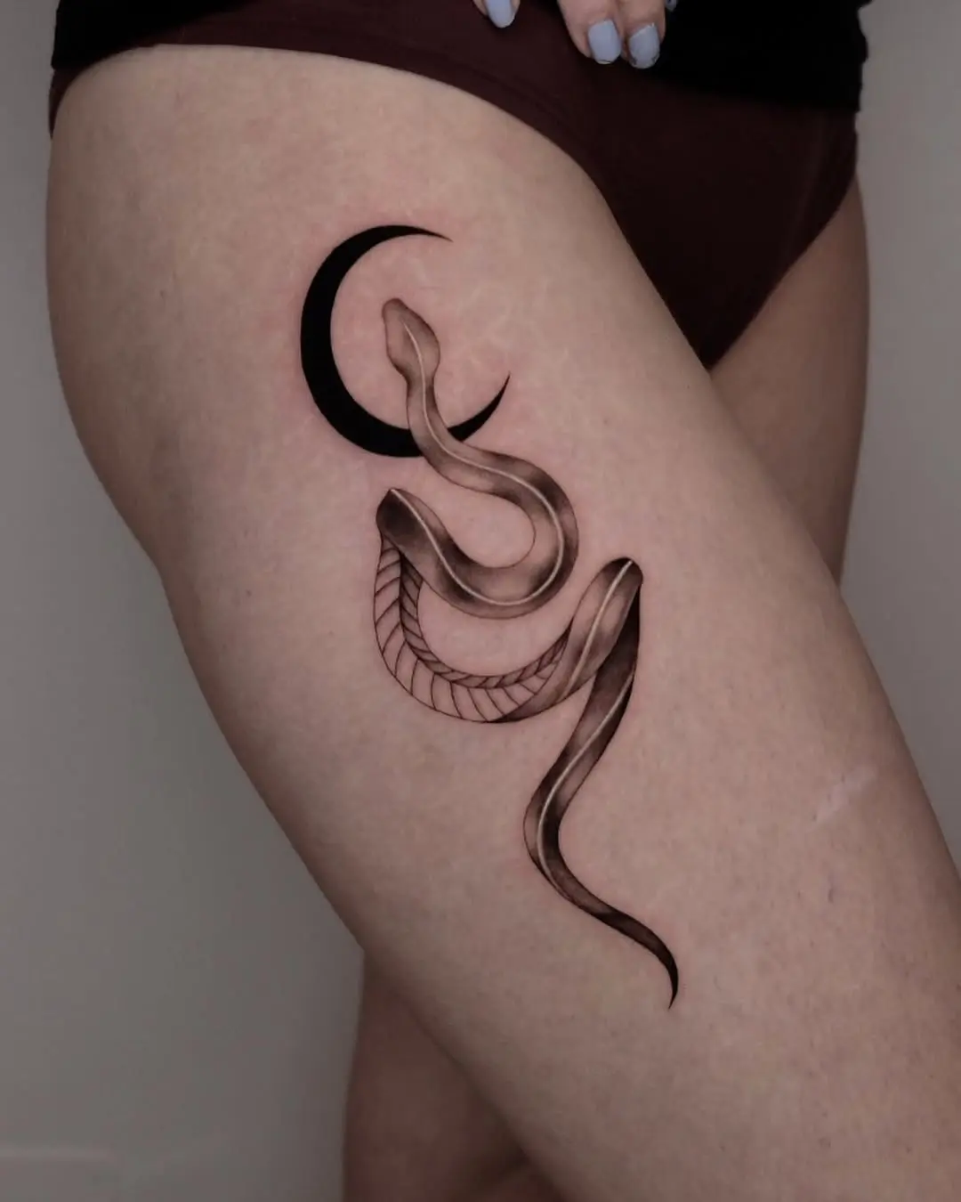 Elegant snake tattoo entwined with a crescent moon