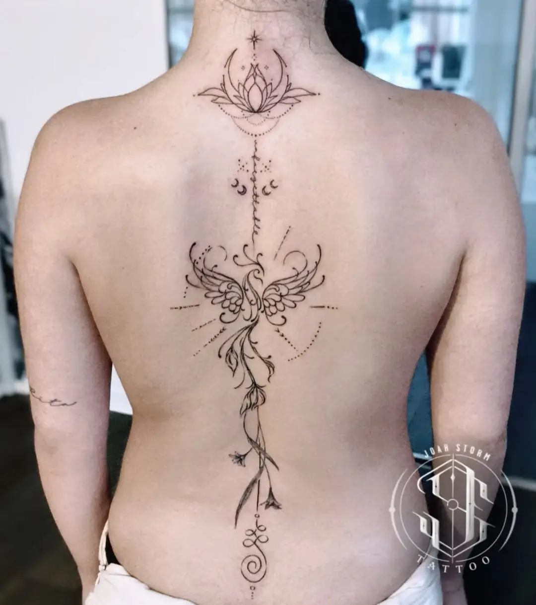 Elegant spine tattoo featuring lotus and floral elements