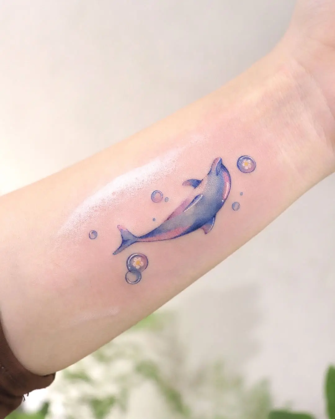 Colorful dolphin tattoo surrounded by playful bubbles