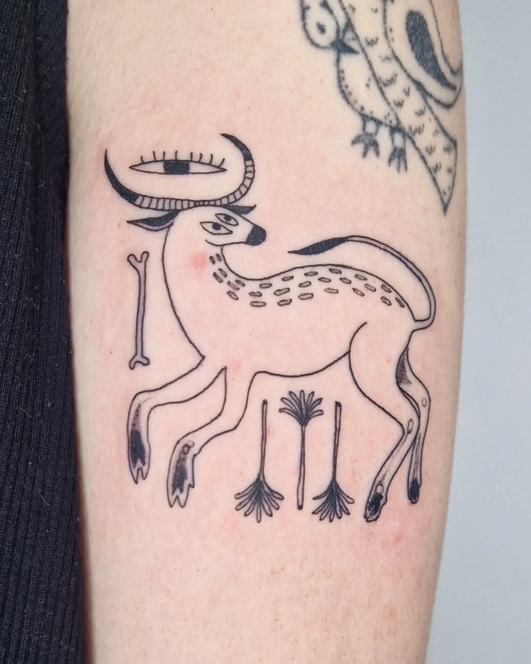 Stylized deer tattoo in black ink