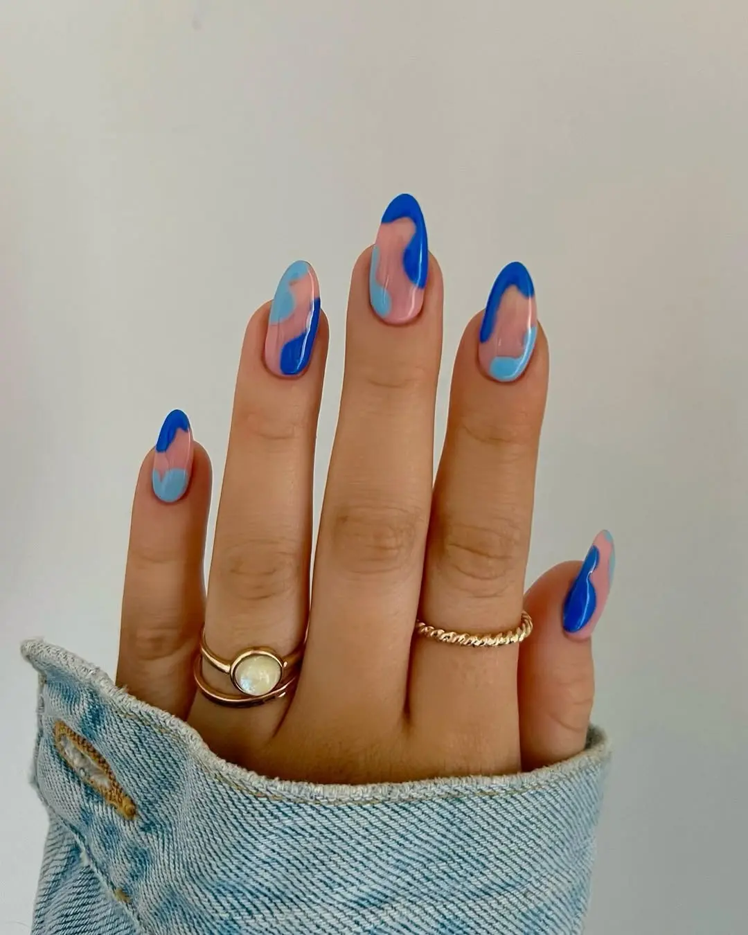 Vibrant blue nails with abstract pastel swirls
