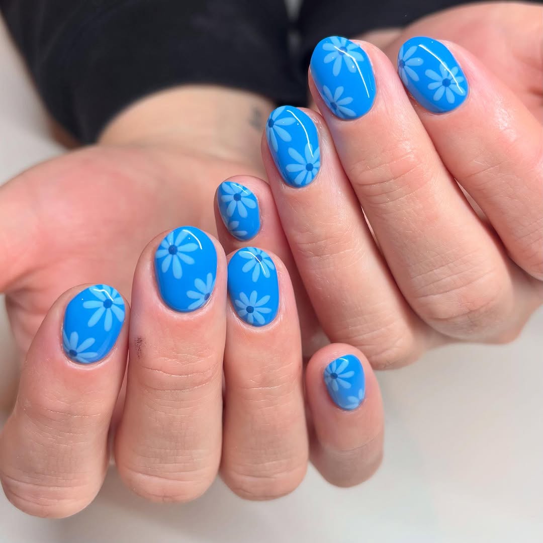 Bright blue nails with delicate floral patterns