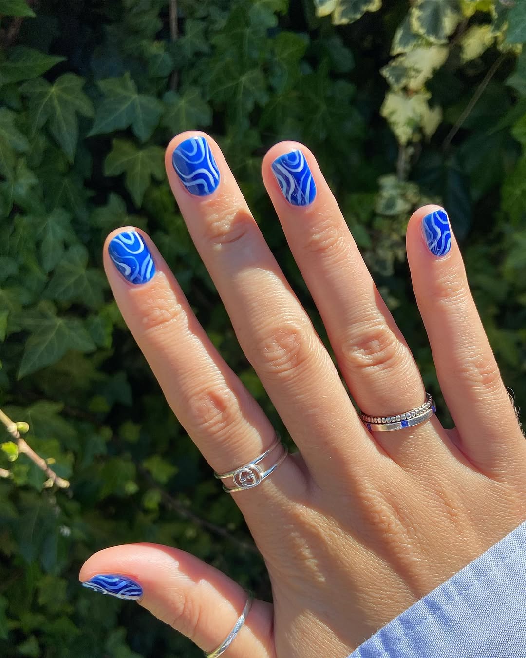 Vibrant blue nails with artistic wave patterns