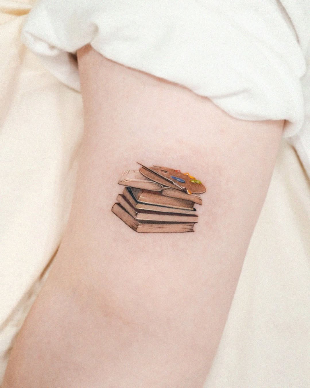 Whimsical stacked books tattoo design on skin