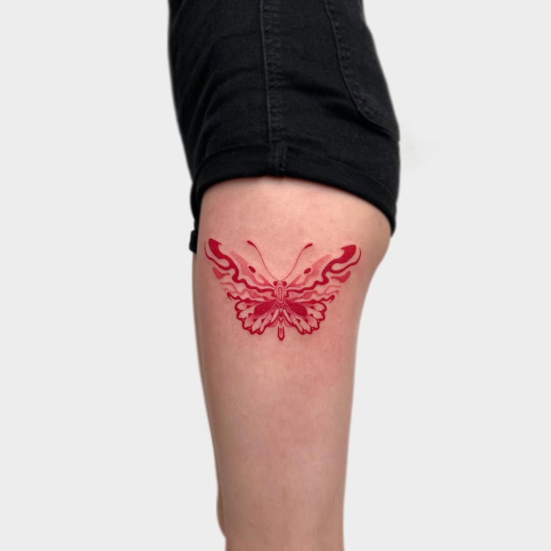 Stunning butterfly thigh tattoo with fiery details
