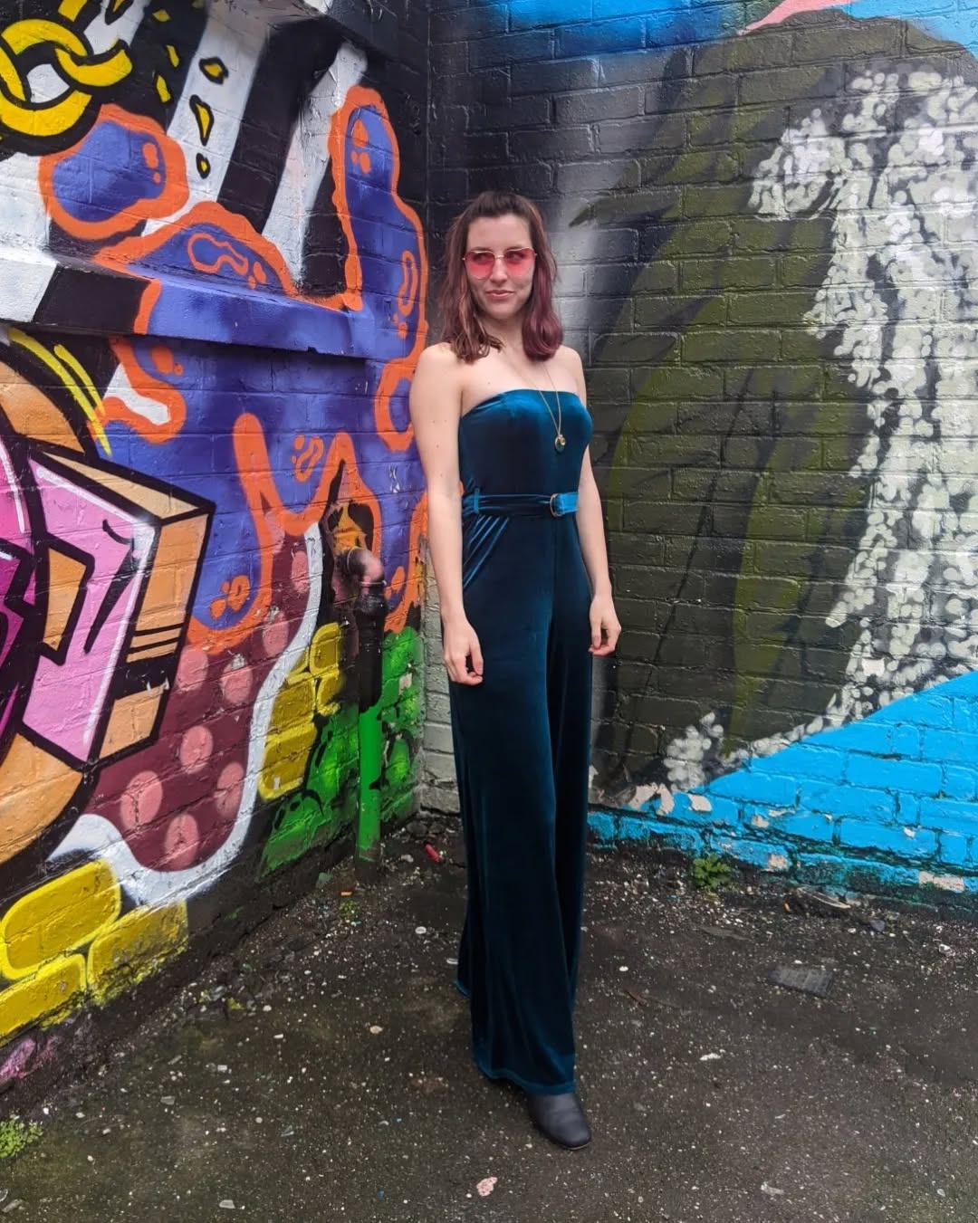 Chic emerald jumpsuit against vibrant street art