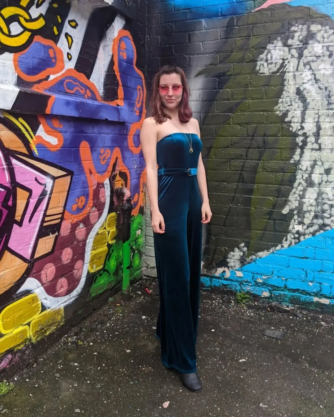Chic emerald jumpsuit against vibrant street art