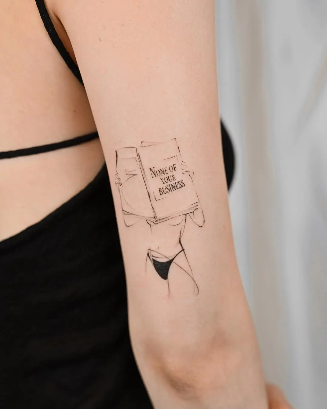 Sassy fine line tattoo with a book