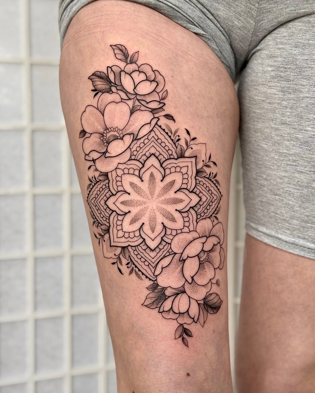 Elegant floral mandala thigh tattoo in black ink