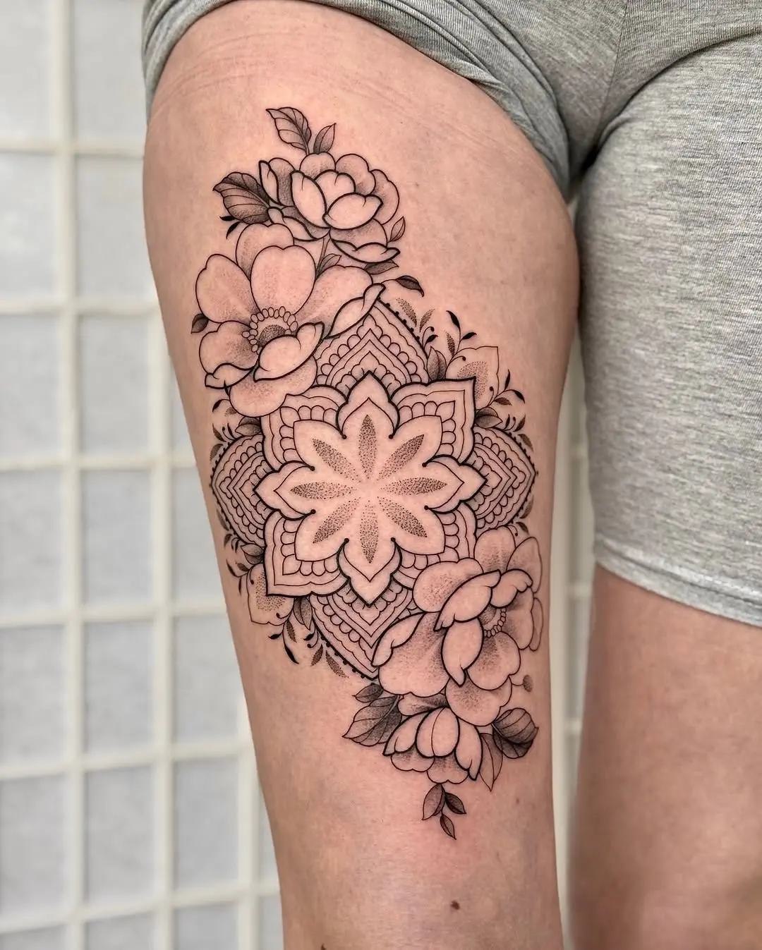 Elegant floral mandala thigh tattoo in black ink