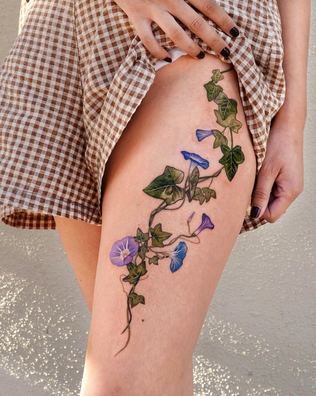 Elegant vines and colorful flowers tattooed on thigh