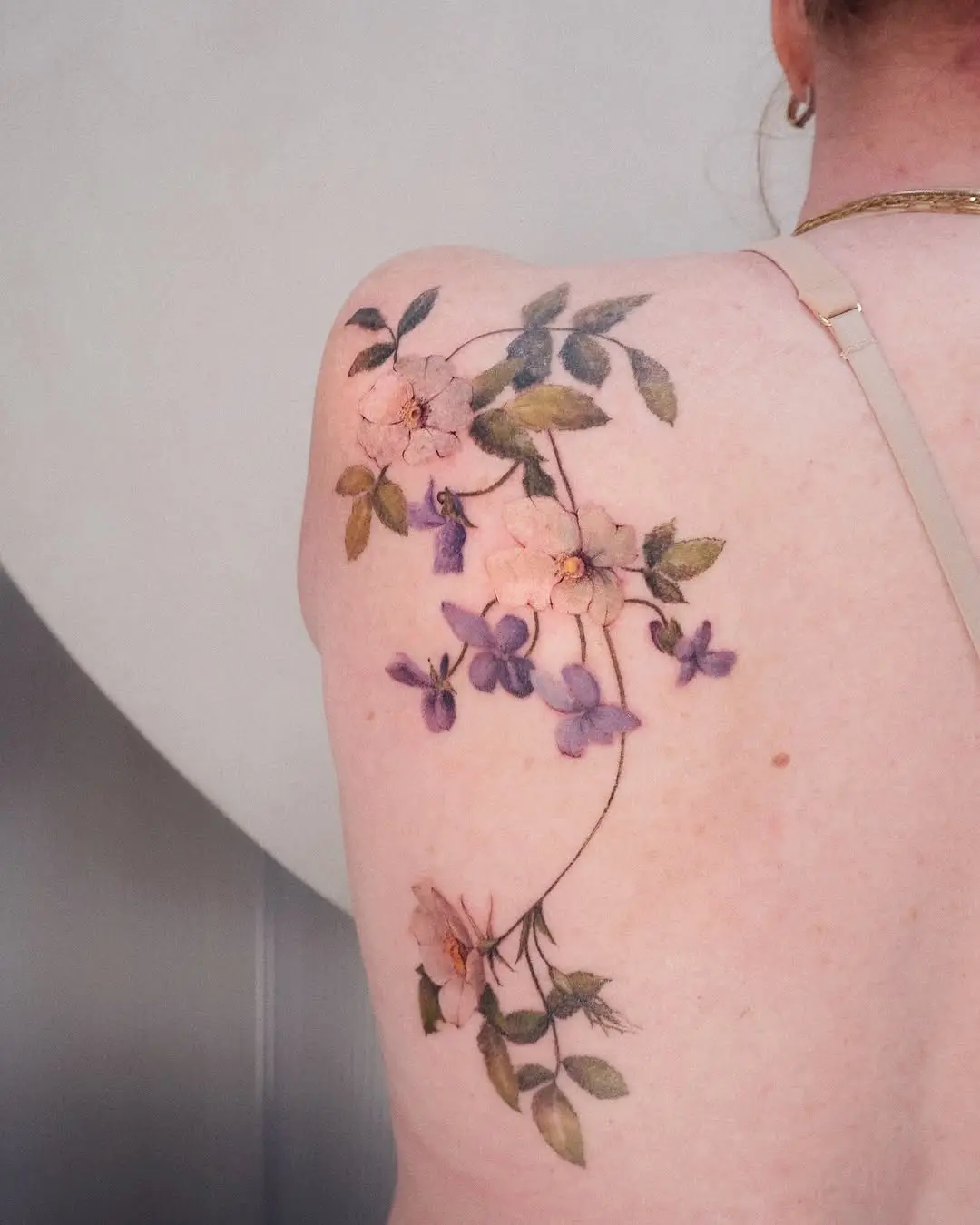 Delicate floral back tattoo with soft colors