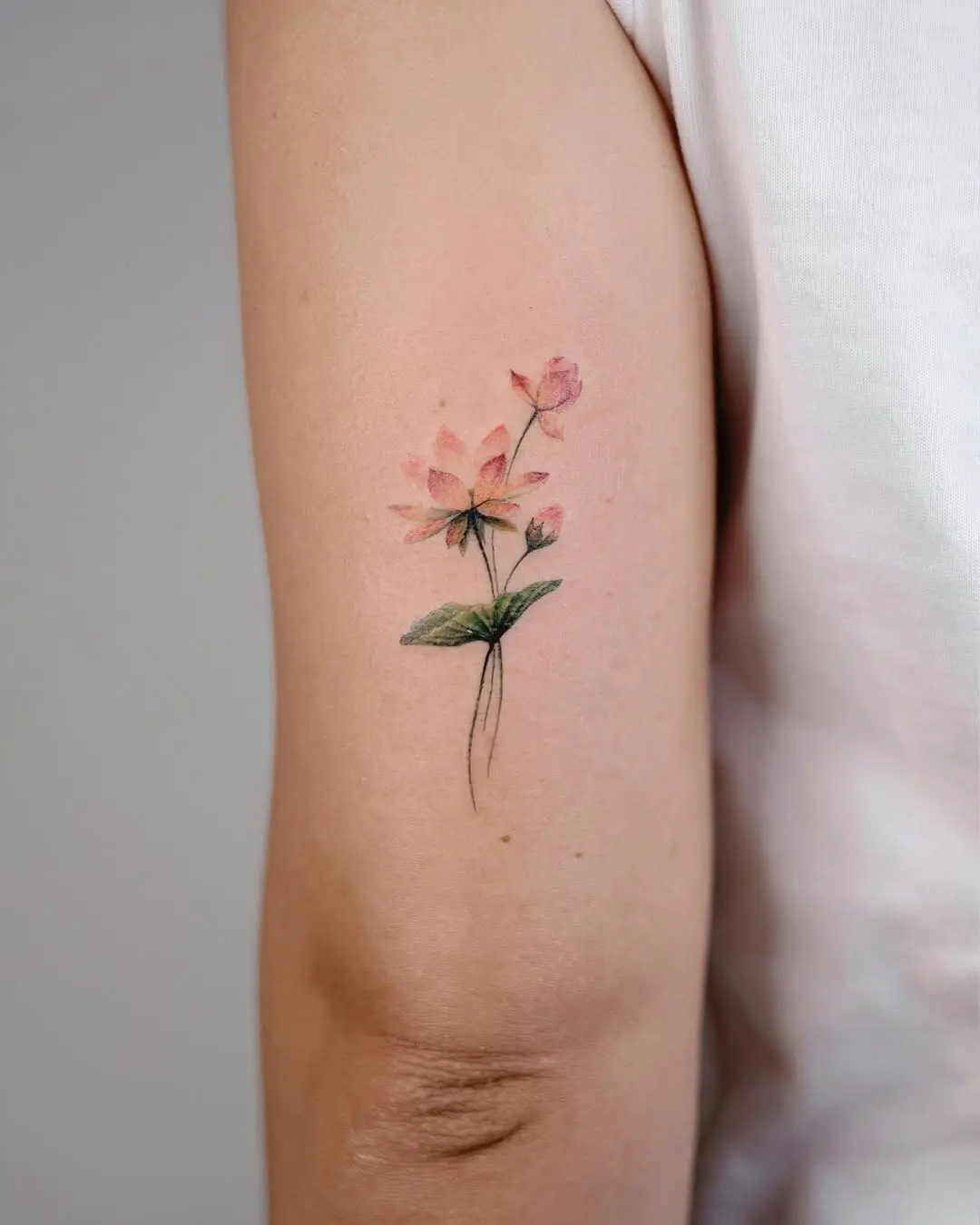 Delicate watercolor rose tattoo on arm
