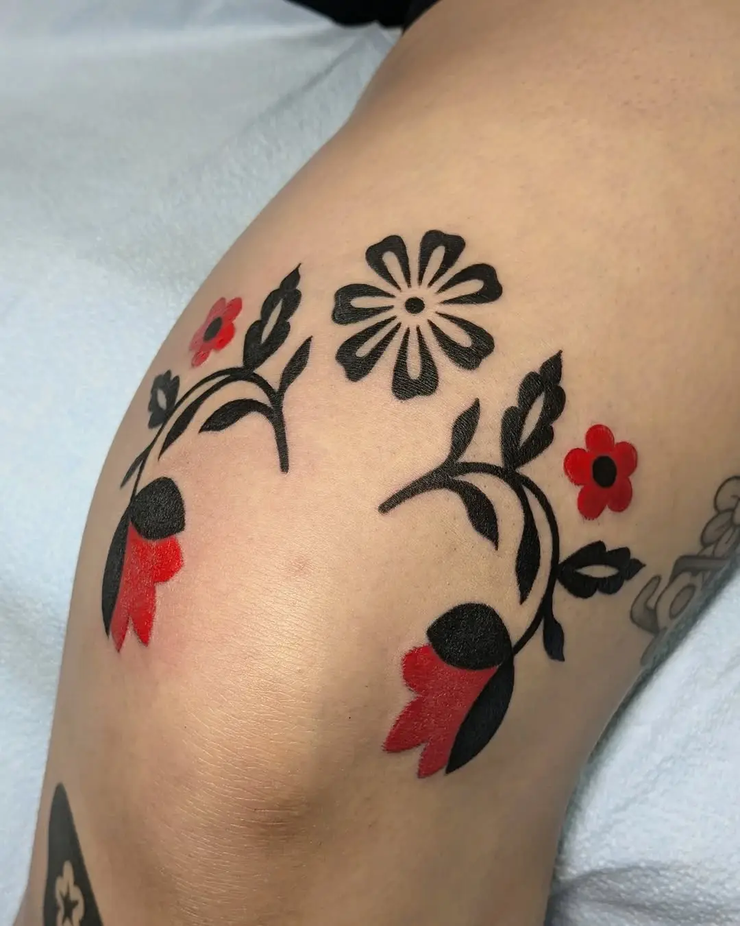 Elegant floral knee tattoo design in black and red