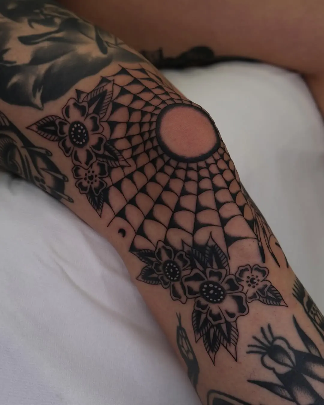 Striking knee tattoo with spider web design