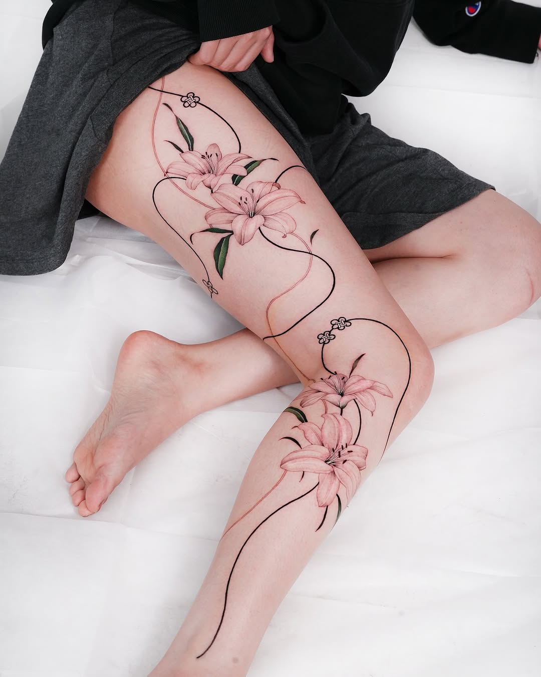 Elegant pink lilies adorn the leg tattoo