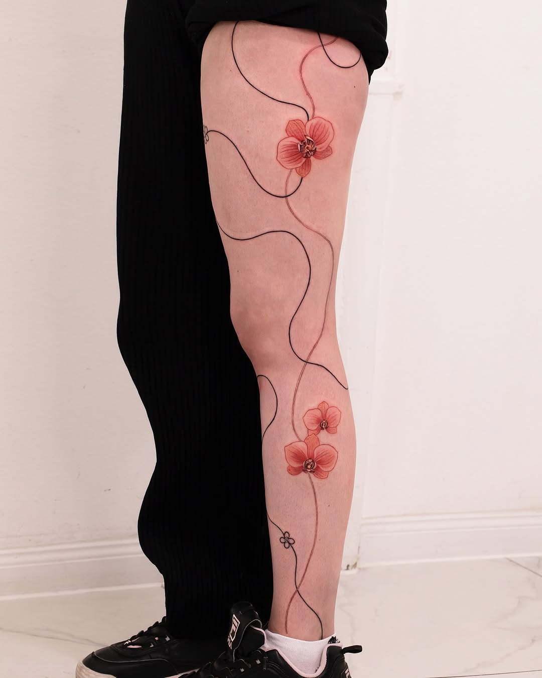 Delicate orchids create elegant leg tattoo design
