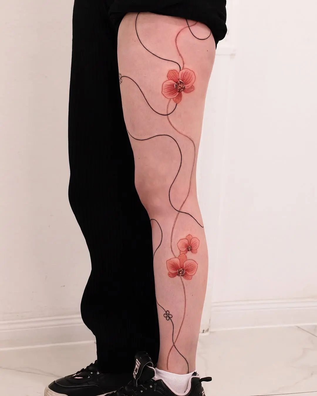 Delicate orchids create elegant leg tattoo design