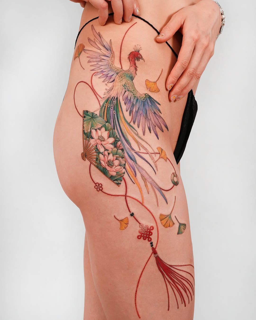 Vibrant phoenix leg tattoo with floral accents