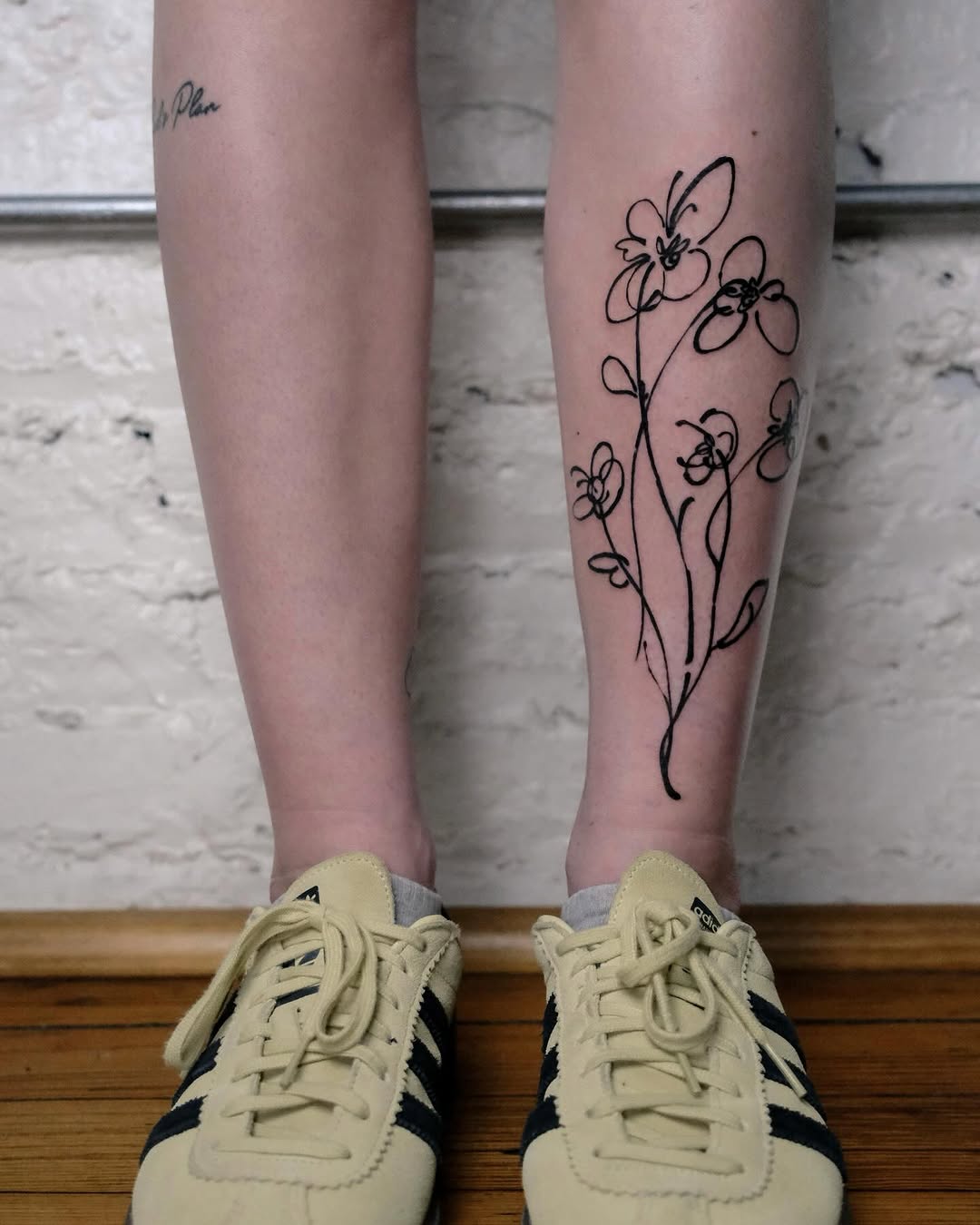 Elegant line art flower tattoo on leg