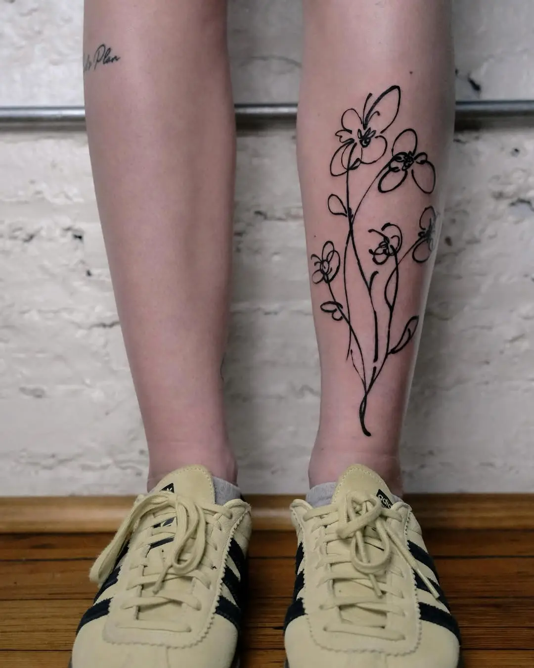 Elegant line art flower tattoo on leg