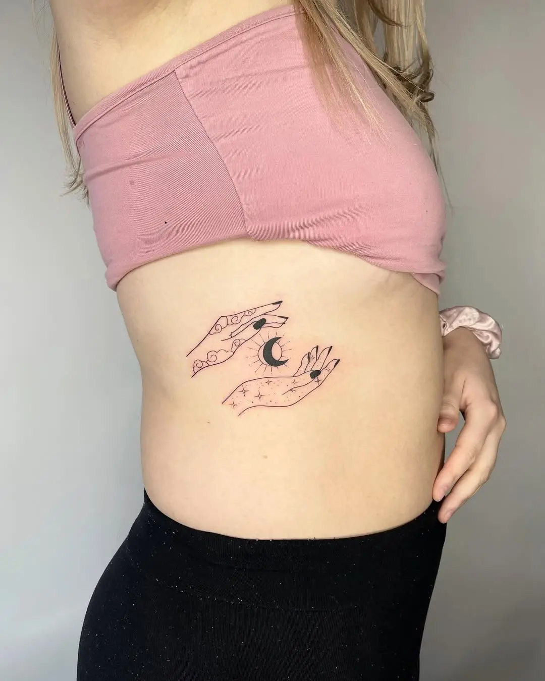 Feminine hands cradling crescent moon tattoo