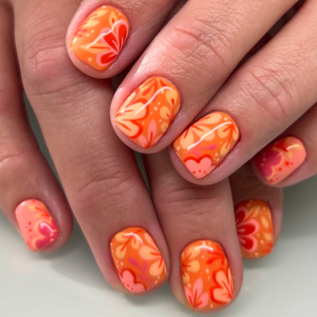 Vibrant floral patterns on bright orange nails