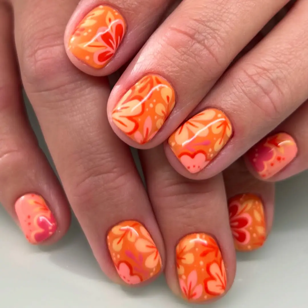 Vibrant floral patterns on bright orange nails