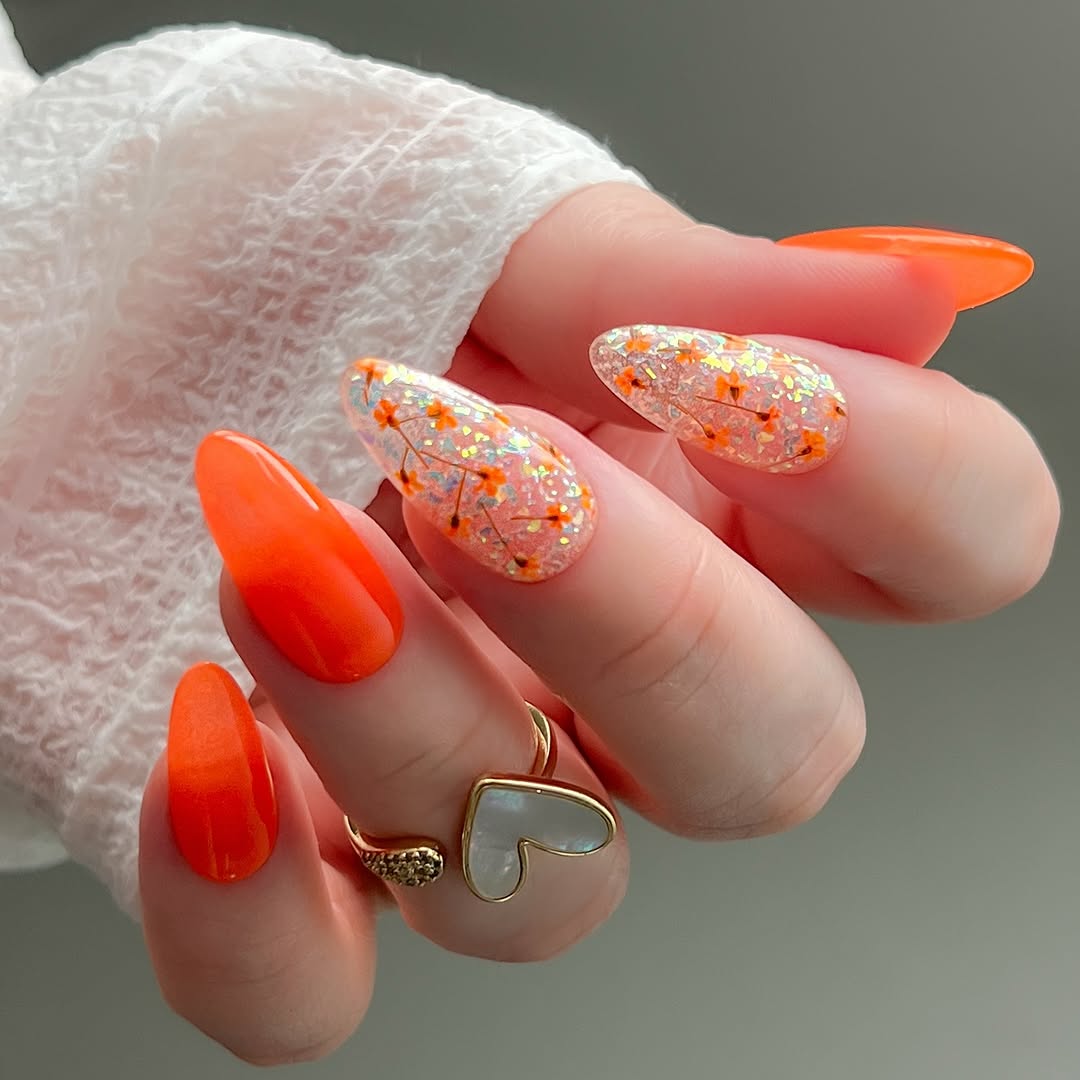 Vibrant orange nails with floral accents