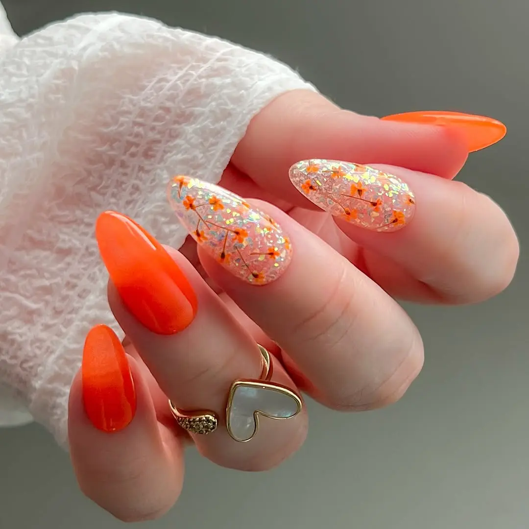 Vibrant orange nails with floral accents