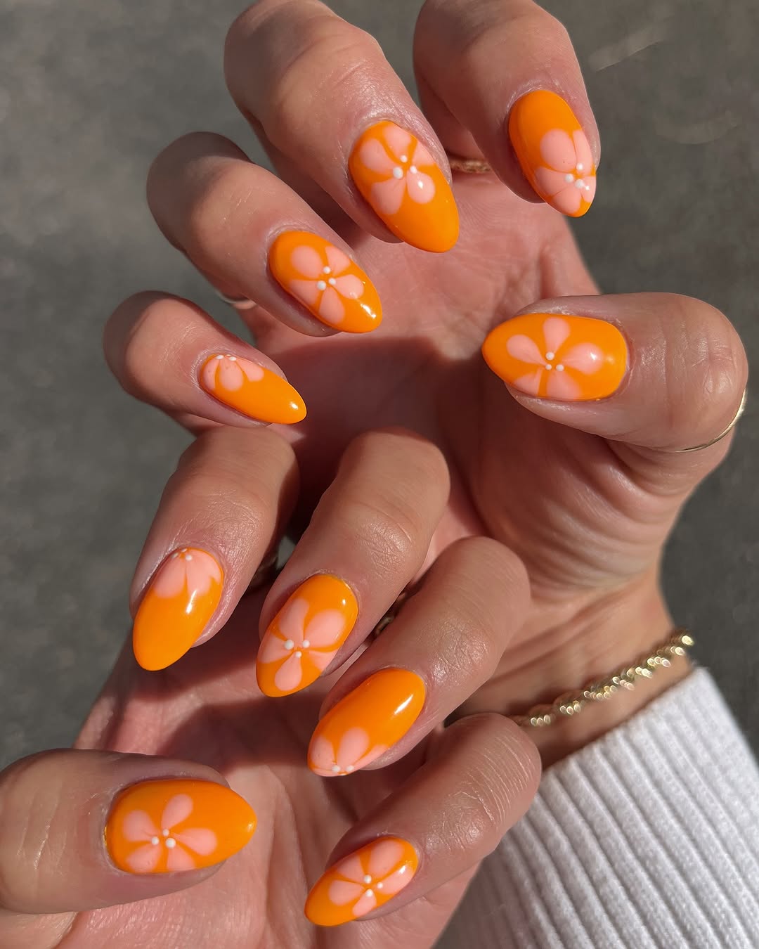Vibrant orange nails with playful flower art